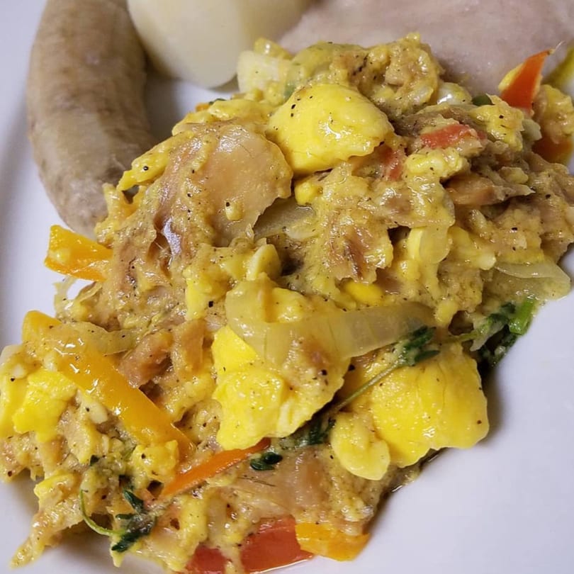 Close-up of Dixon's Jamaican ackee and saltfish with boiled dumplings on a white plate.